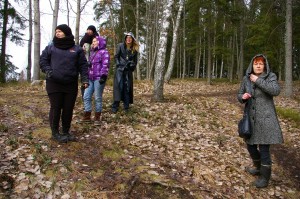 Muinaistaidetyöpajan osallistujat Rapolan harjulla kuulemassa Riitta Virtasen (oik.) kertomusta muinaisen ihmisen maailmankuvasta.