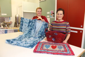 Tekstiilityön opettaja Riitta Ala-Krekola esittelee kimonoa, jonka urjalalainen Arja Salminen on tehnyt vanhoista lakanoista. Kuviot on tehty kuviovärjäyksellä. Tuula Kahila on huovuttanut korin ja tehnyt jämälangoista räsyvirkkauksella maton. 