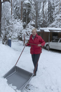 Arja Raiski pitää pihan puhtaana kolaamalla. Viikonloppuna runsas lumentulo tiesi tuntien lumitöitä. 